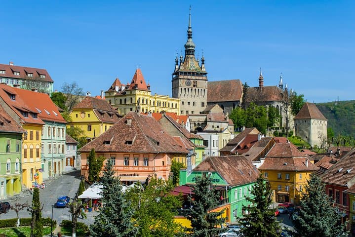 Medieval town square with colorful pastel houses and a tall clock tower under clear blue sky